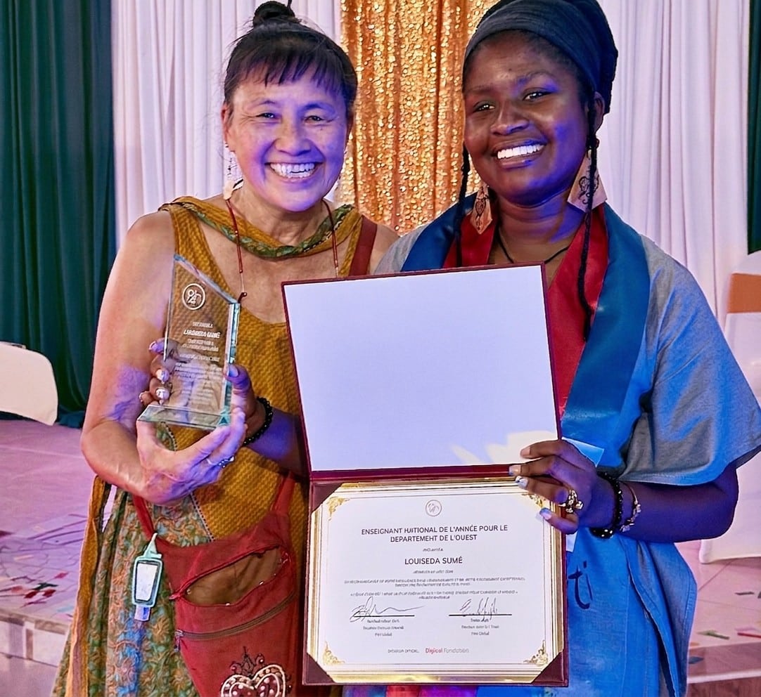 Chris stands with Louiseda as she holds her certificate recognizing her as one of Haiti's top 10 teachers.